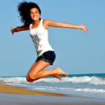 Smiling Woman Jumps For Joy On Beach