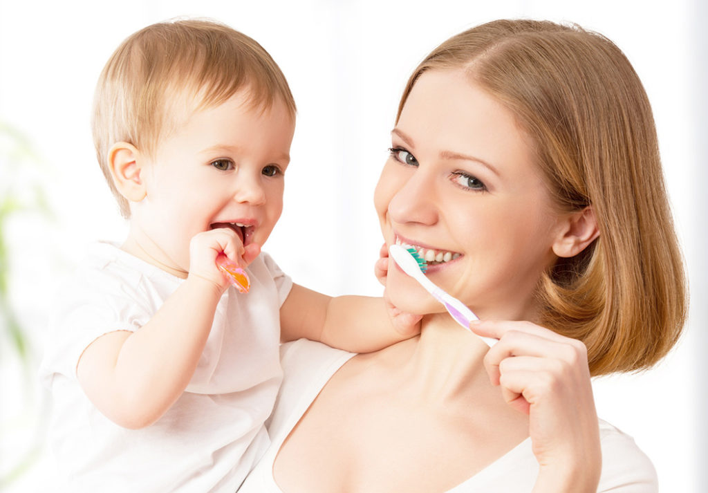 Happy Mother and Baby With Tooth Brushes After Healthy Pregnancy